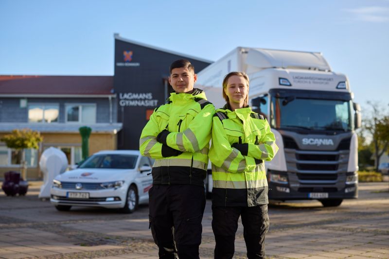 Två elever framför en lastbil.
