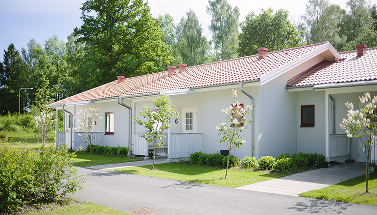 Vitt radhus i ett plan med träd planterade framför varje entré.