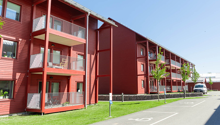 Exteriör bild av rött trevåningshus med balkonger.