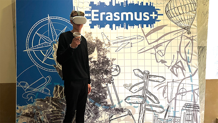 Man med VR-glasögon står framför en bildbakgrund med texten Erasmus+.