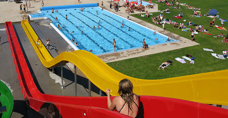 En tjej sitter redo att åka vattenrutschkana på utomhusbadet.